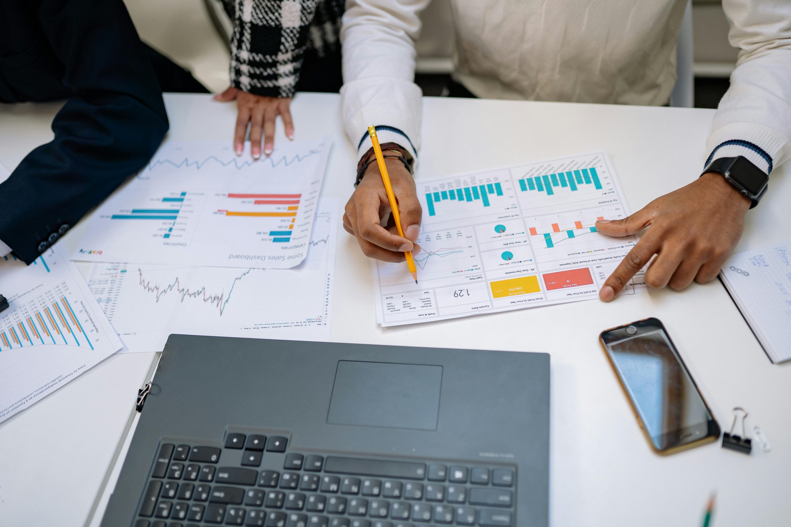 Travail d'équipe sur les rapports de données - mygrowthbox.com Mains d'équipe sur une table avec des papiers et des graphiques de données pour l'unification client - mygrowthbox.com